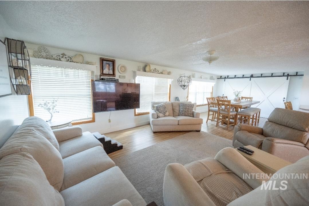 Living room featuring a barn door, a textured ceiling, wood finished floors, and rail lighting