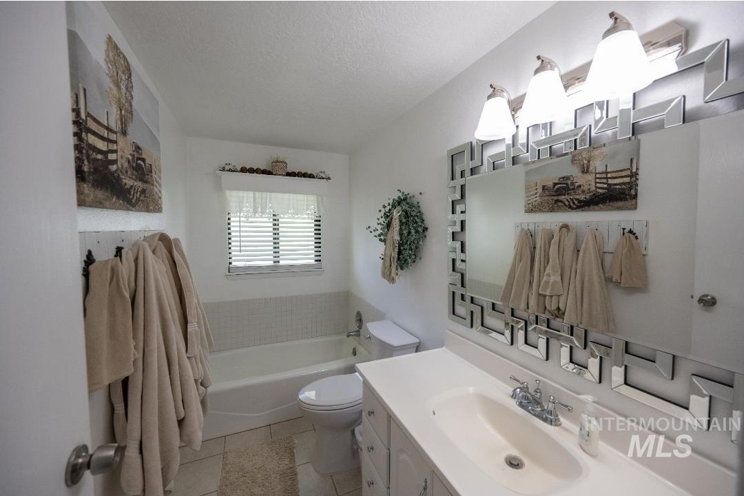 Bathroom featuring a bath, vanity, a textured ceiling, and light tile patterned floors