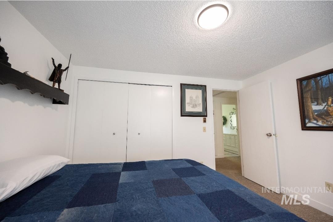 Unfurnished bedroom with a textured ceiling, carpet floors, and a closet