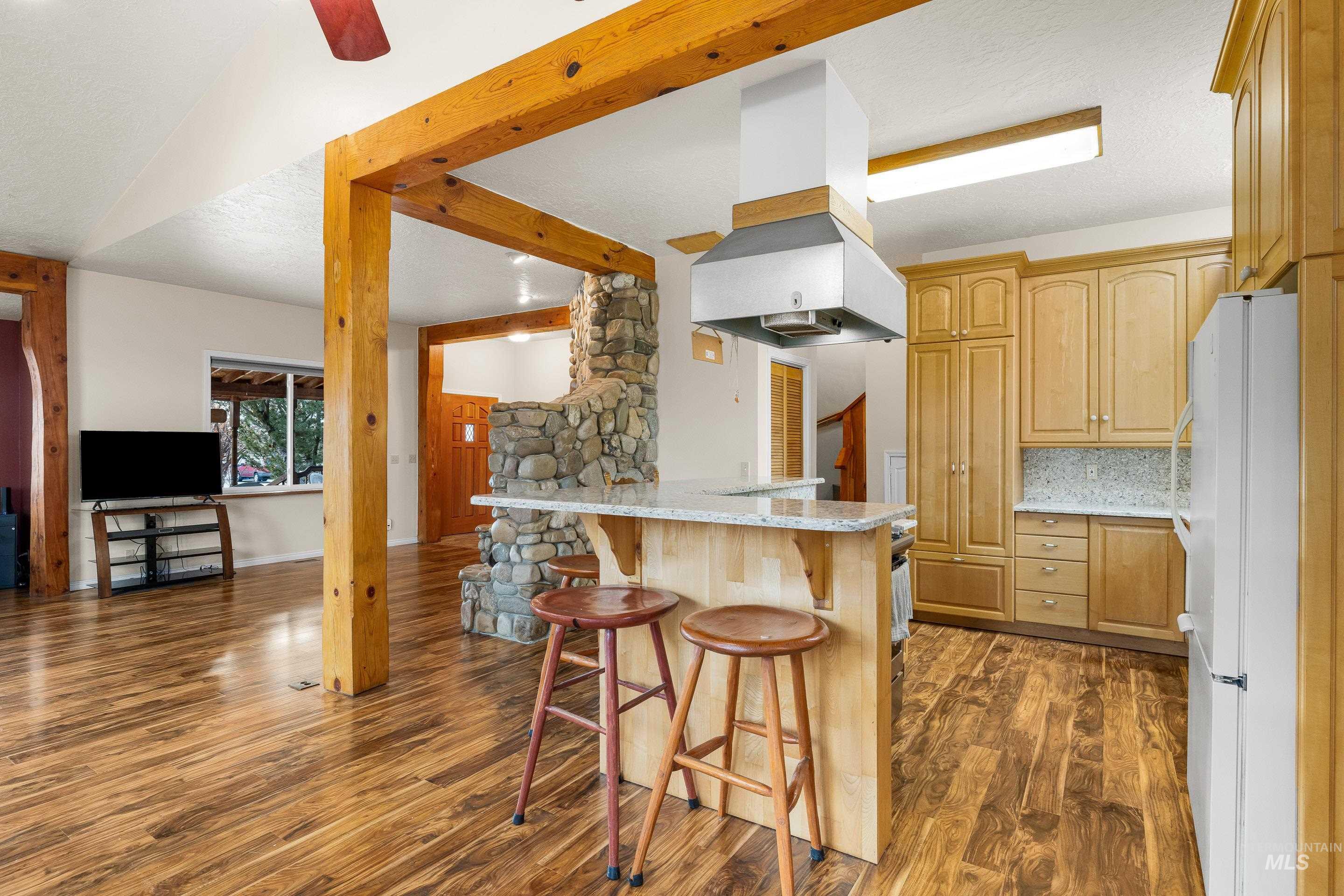 Kitchen with freestanding refrigerator, a kitchen bar, a textured ceiling, decorative backsplash, and light stone counters