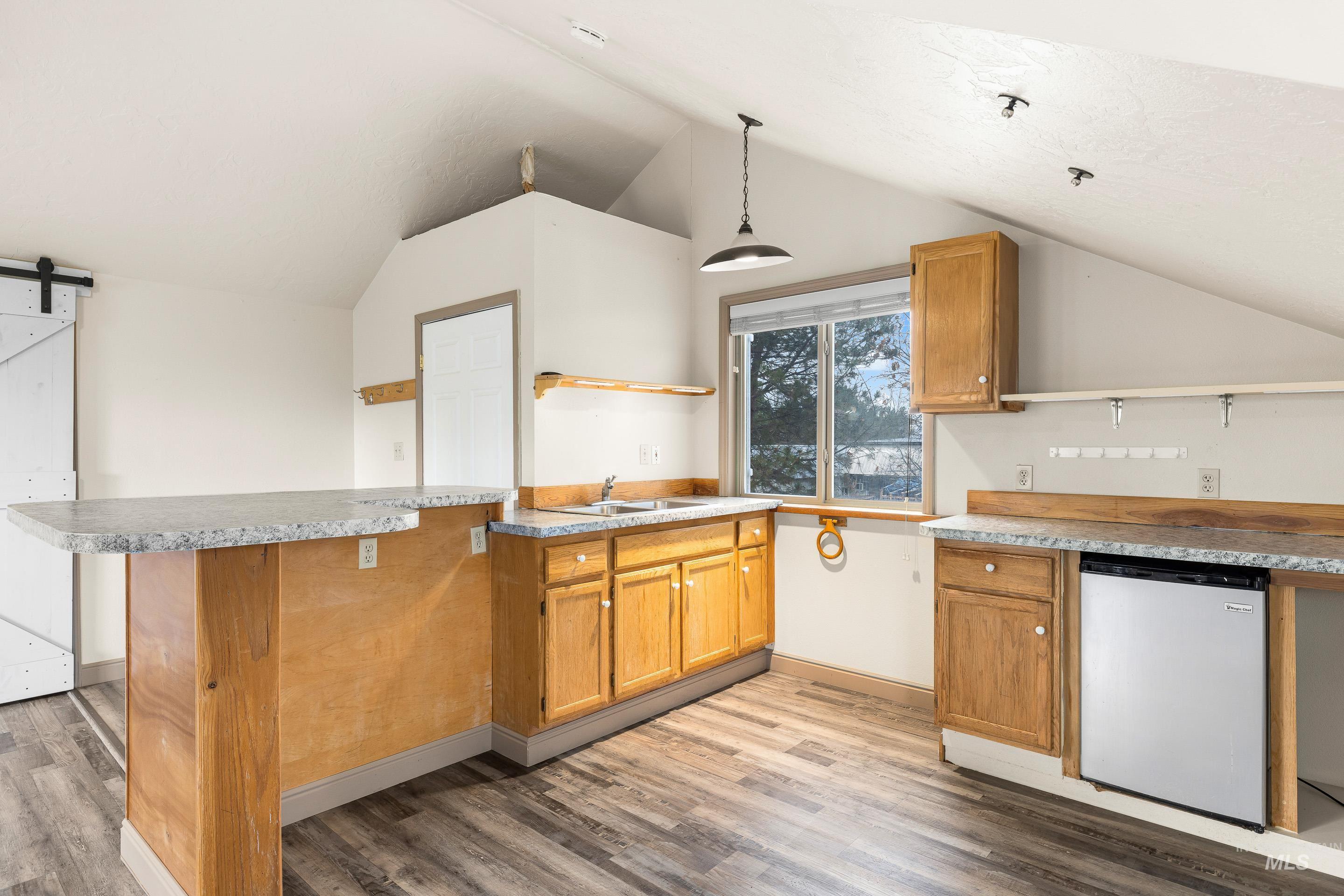Kitchen with open shelves, a barn door, a peninsula, light countertops, and dishwasher