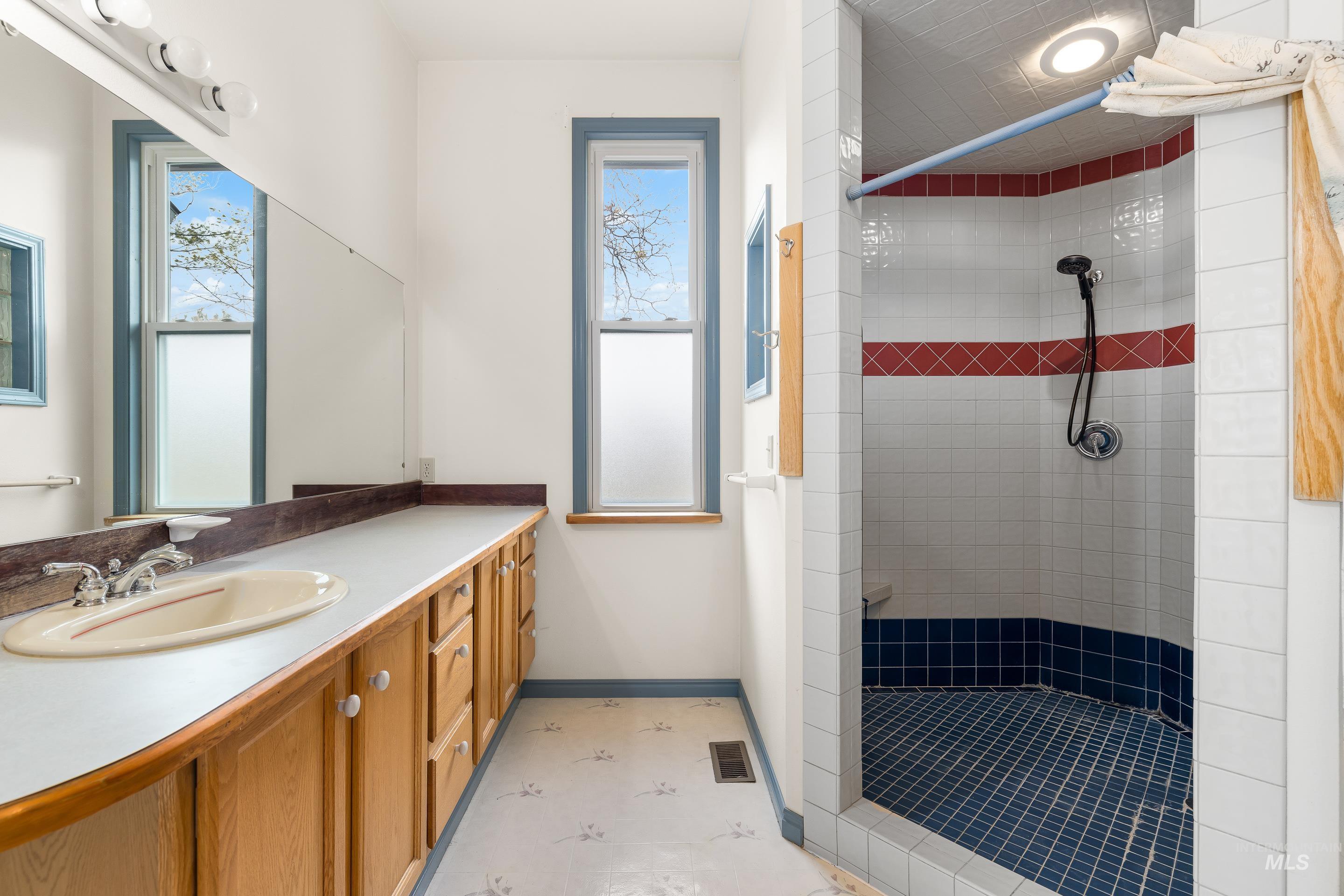 Full bath featuring vanity, a shower stall, and healthy amount of natural light