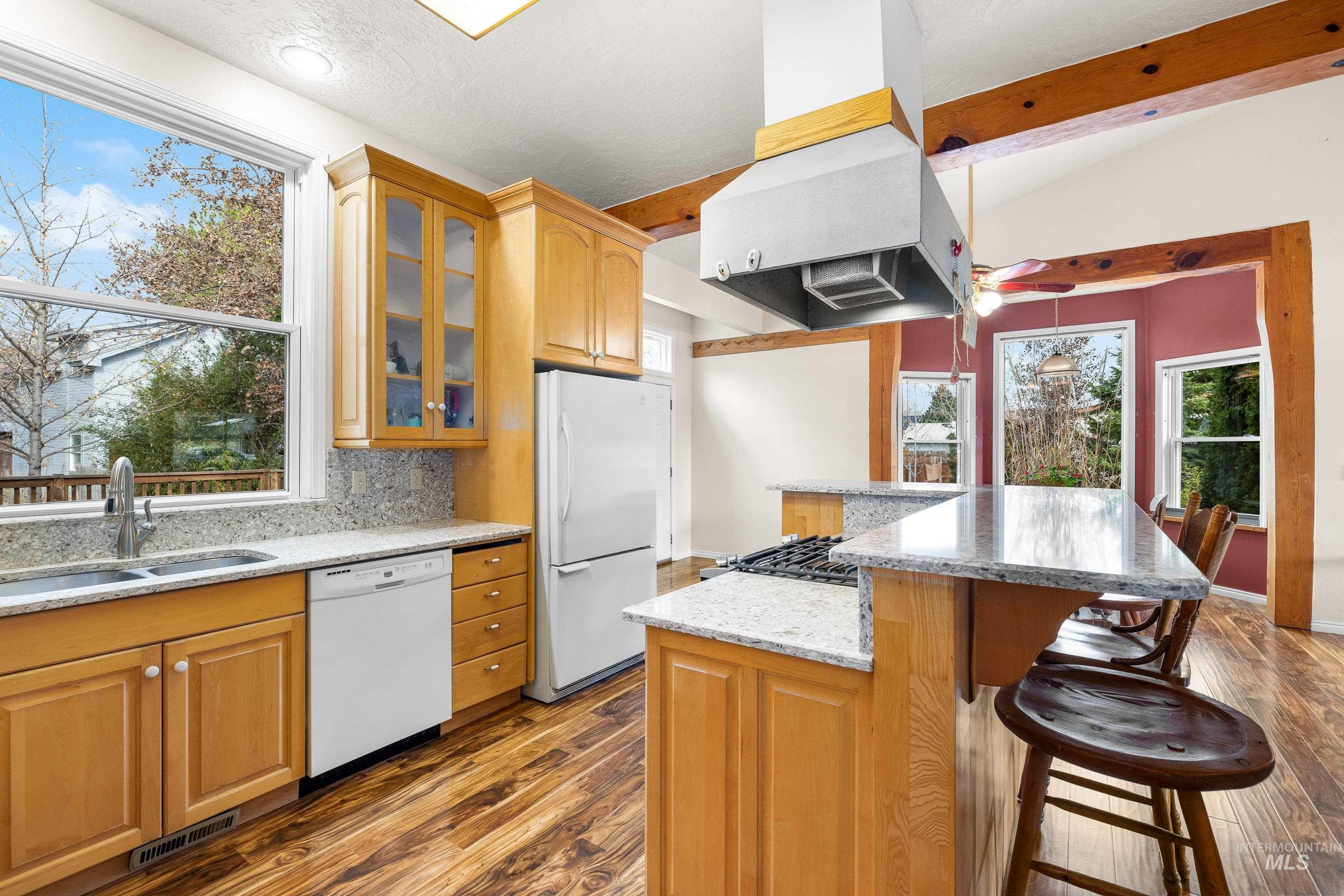 Kitchen featuring dark wood-style floors, white appliances, light stone counters, exhaust hood, and glass insert cabinets