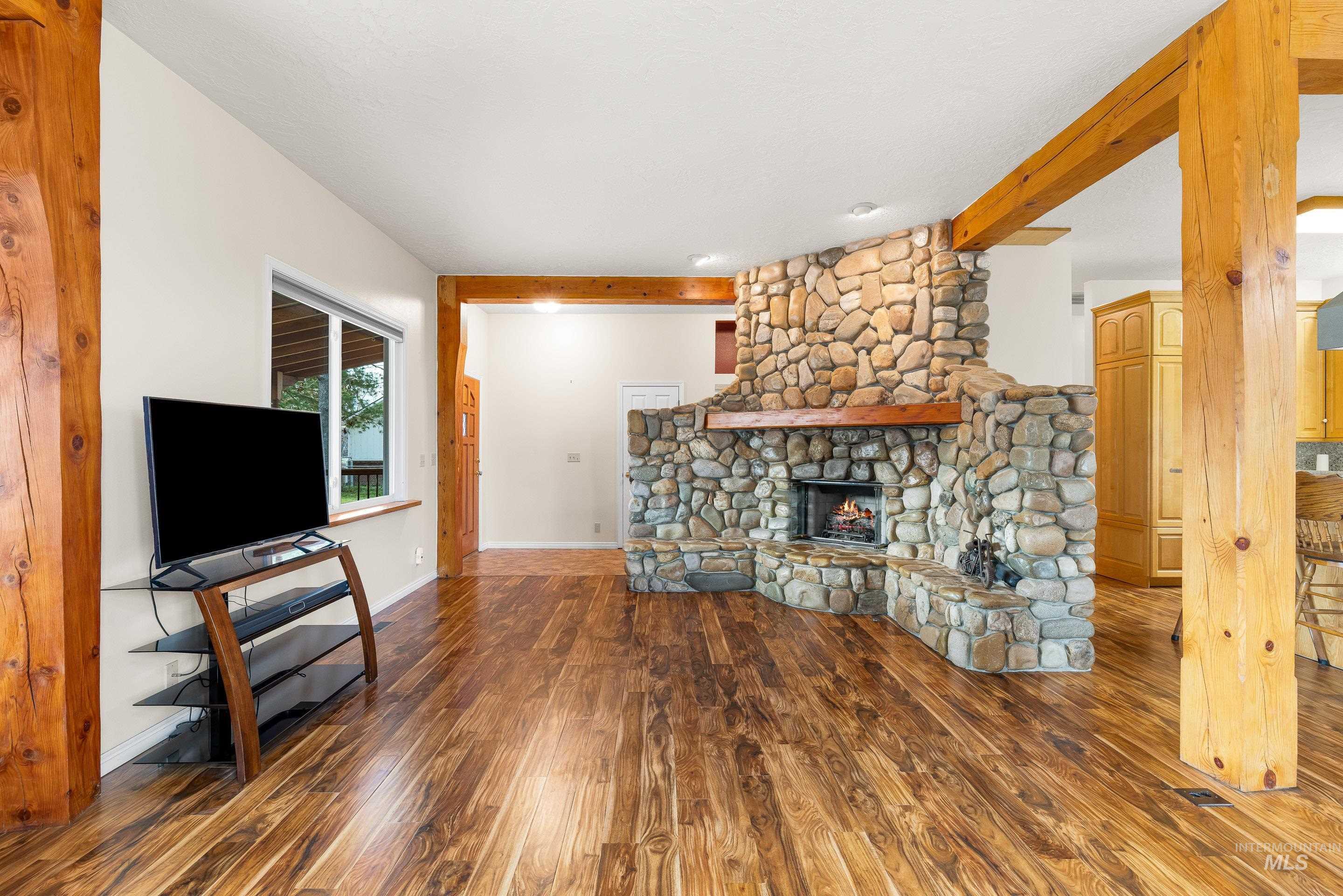 Living room with dark wood-style flooring, a fireplace, and beam ceiling