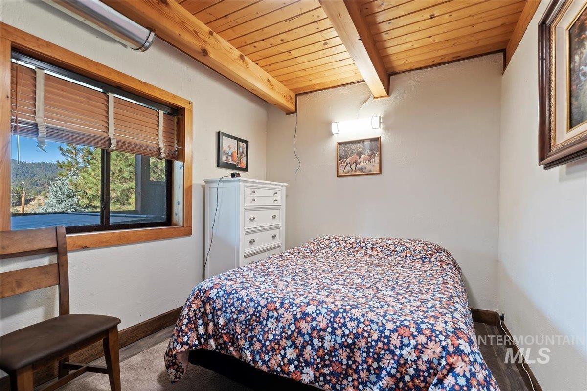 Bedroom featuring a wood ceiling with exposed beams and baseboards