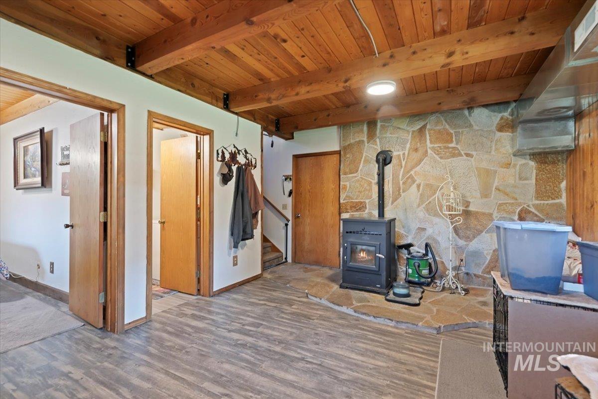 Below grade area featuring a wood stove, wooden ceiling, wood finished floors, and stairs