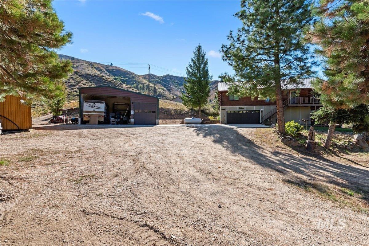 View of front of property featuring a mountain view, a garage, dirt driveway, and stairway
