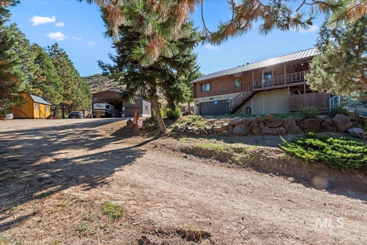 View of front of property with stairway, driveway, a metal roof, and an outbuilding