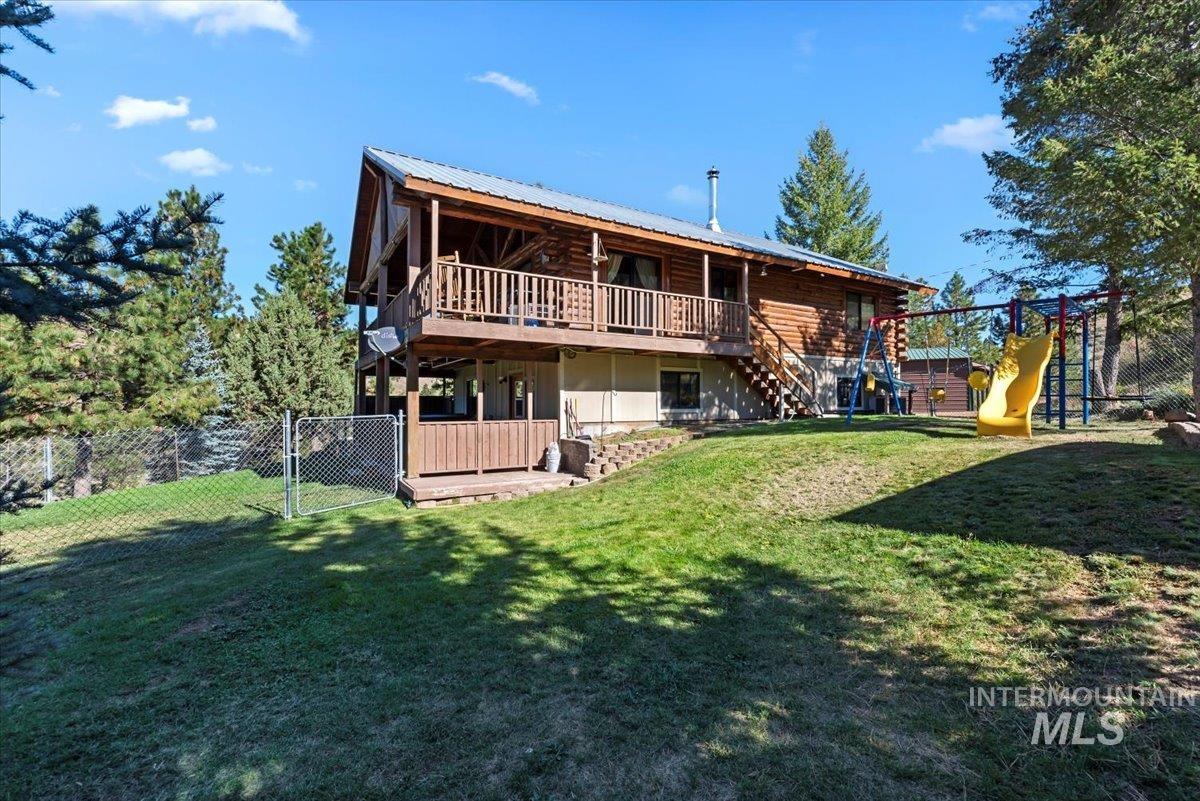 Rear view of house featuring a deck, stairway, log siding, a gate, and a playground