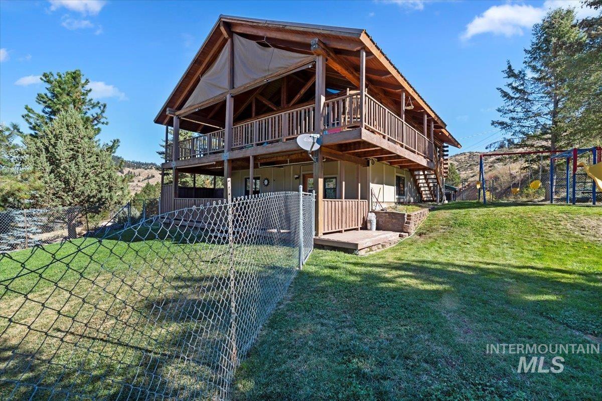 Rear view of house with a deck, board and batten siding, a playground, and stairs