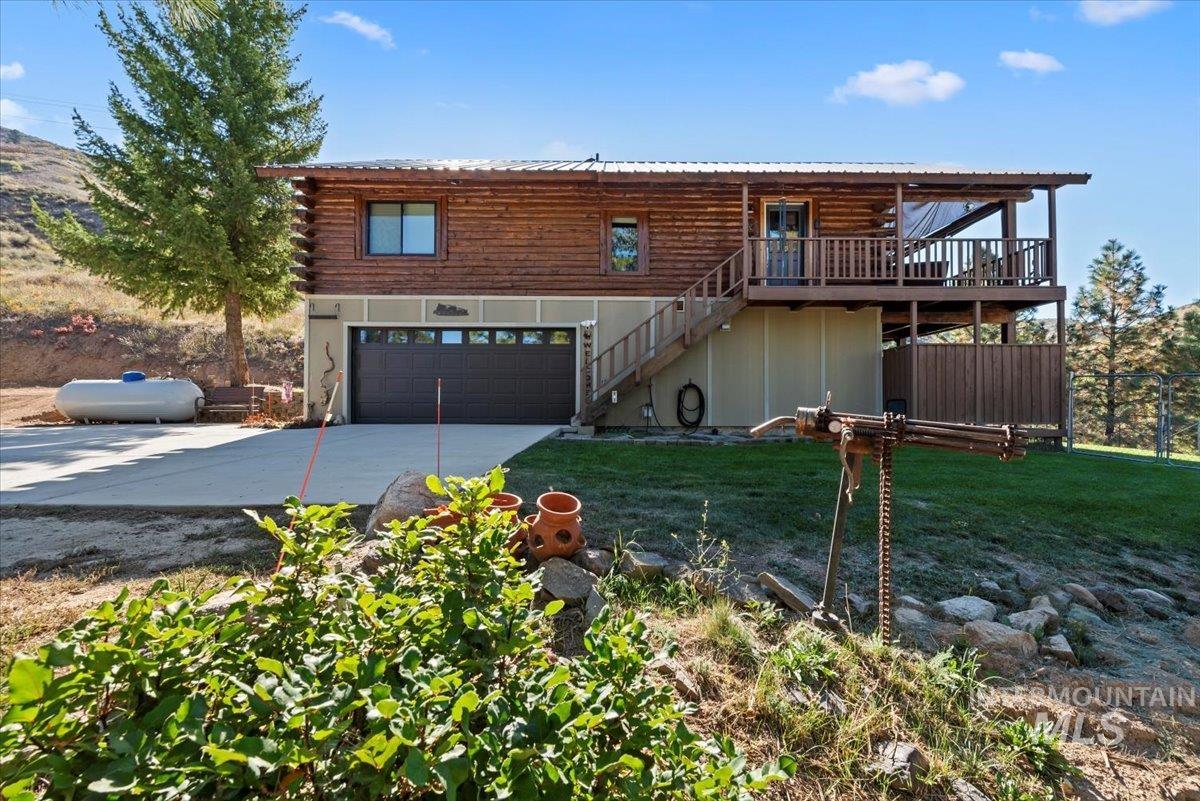 Log cabin featuring stairs, driveway, a front yard, a deck, and log siding