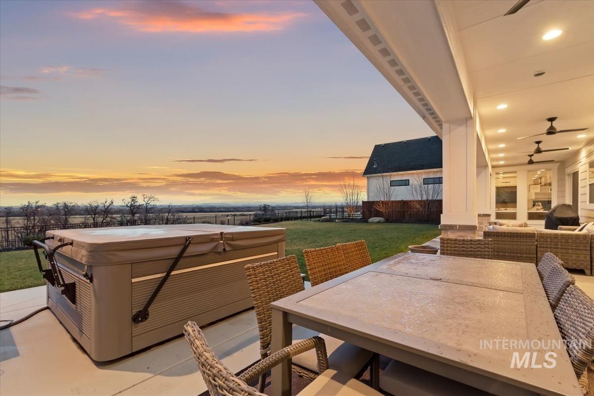 Fenced backyard with a patio, an outdoor living / dining area, a hot tub, a ceiling fan, and area for grilling