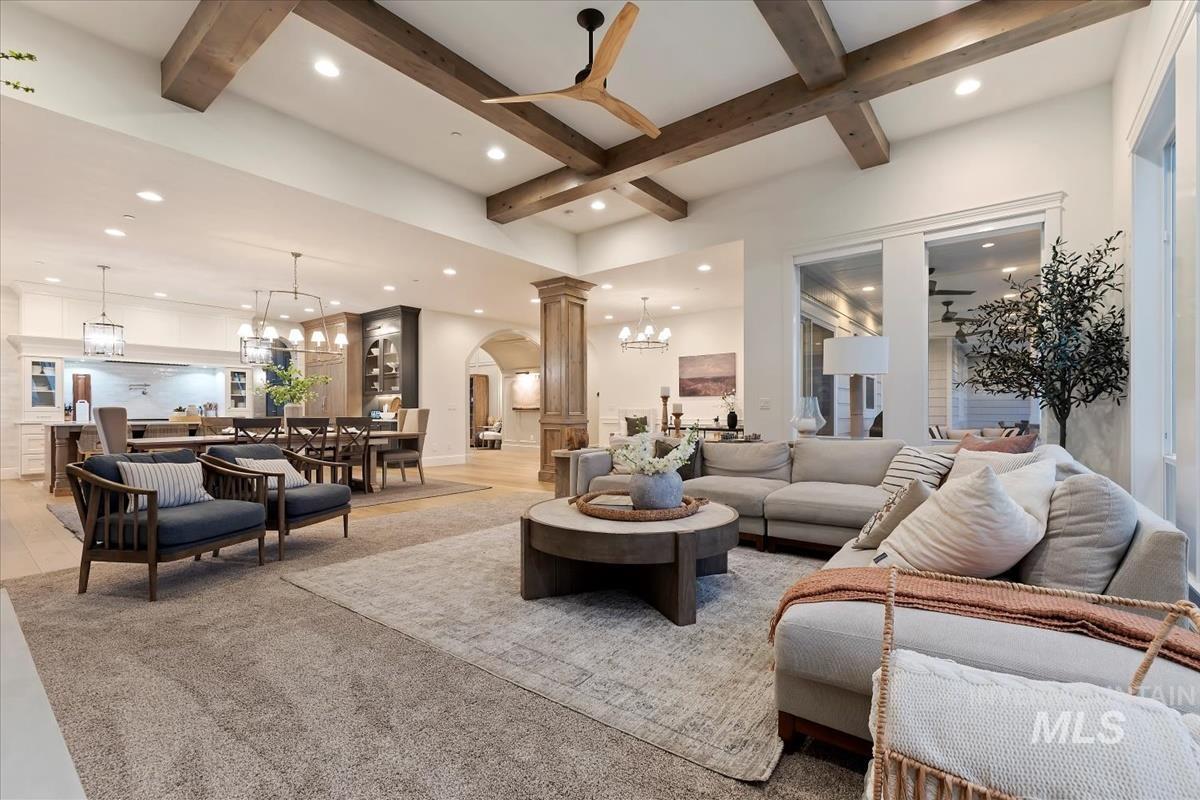 Living room featuring a chandelier, arched walkways, ceiling fan, coffered ceiling, and carpet flooring