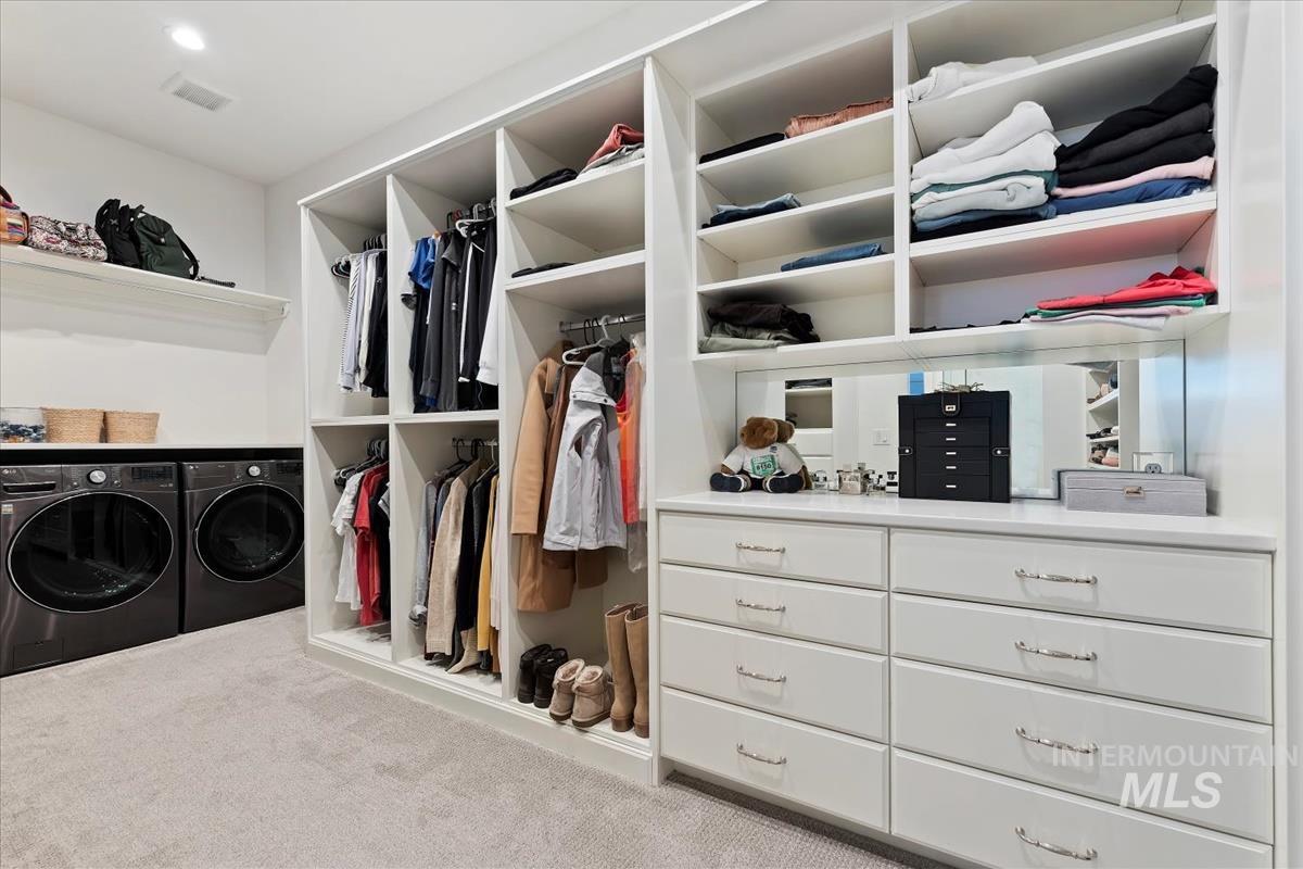 Walk in closet with carpet floors and washing machine and clothes dryer