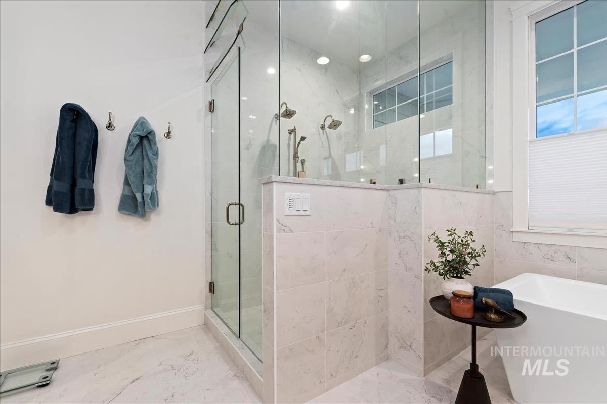 Full bathroom featuring a marble finish shower, a freestanding tub, and marble finish floors