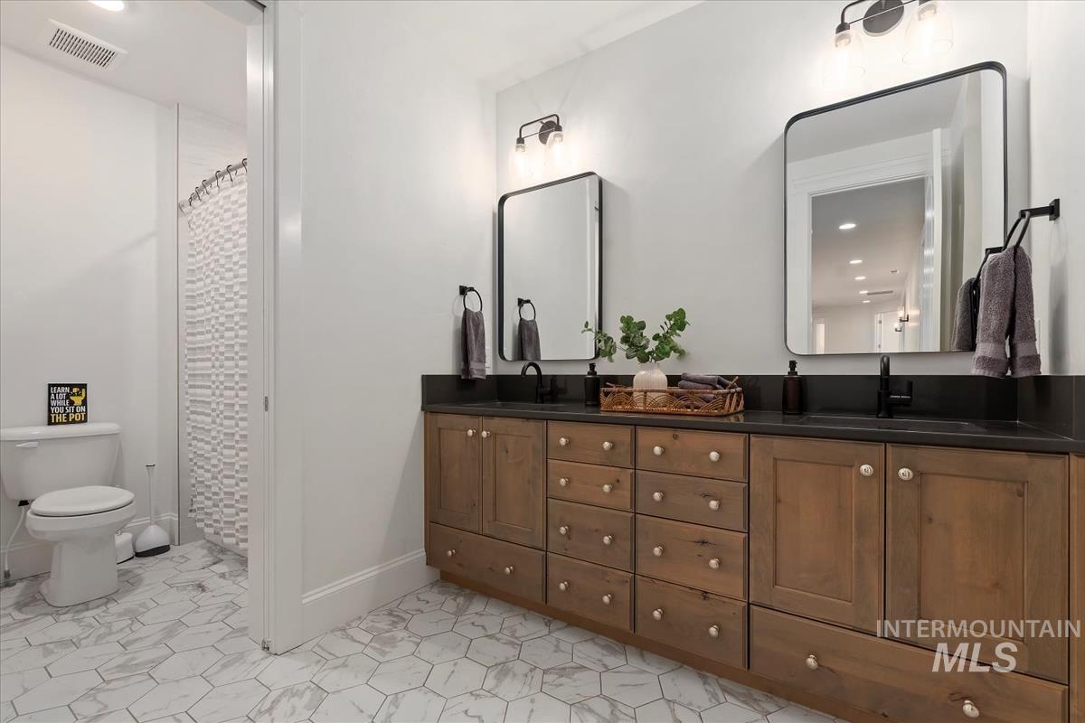 Full bathroom with double vanity, recessed lighting, and a shower with curtain