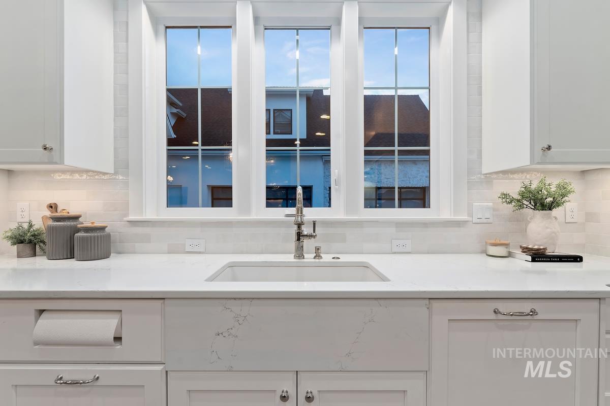 Kitchen with white cabinetry, tasteful backsplash, and light stone countertops