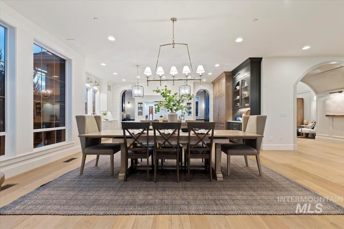 Dining room with arched walkways, light wood-style floors, and recessed lighting