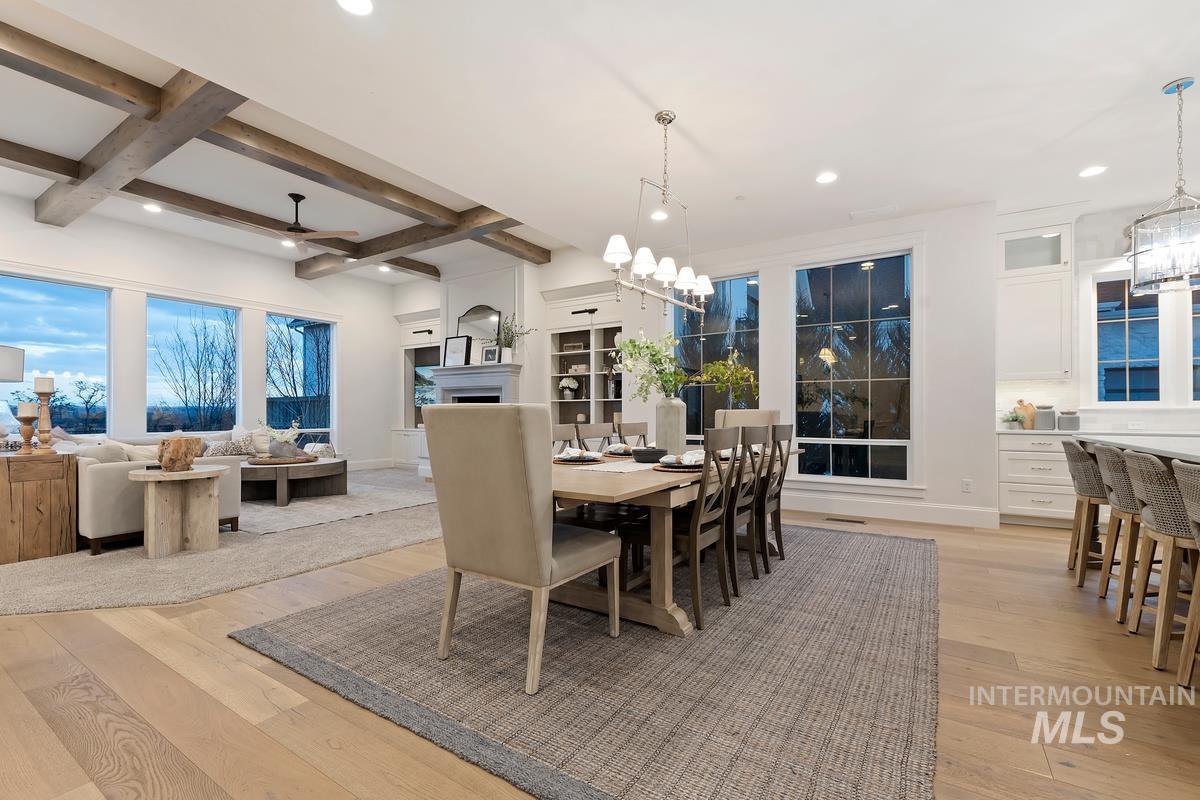 Dining area with hanging lights, light wood-style flooring, coffered ceiling, and a ceiling fan