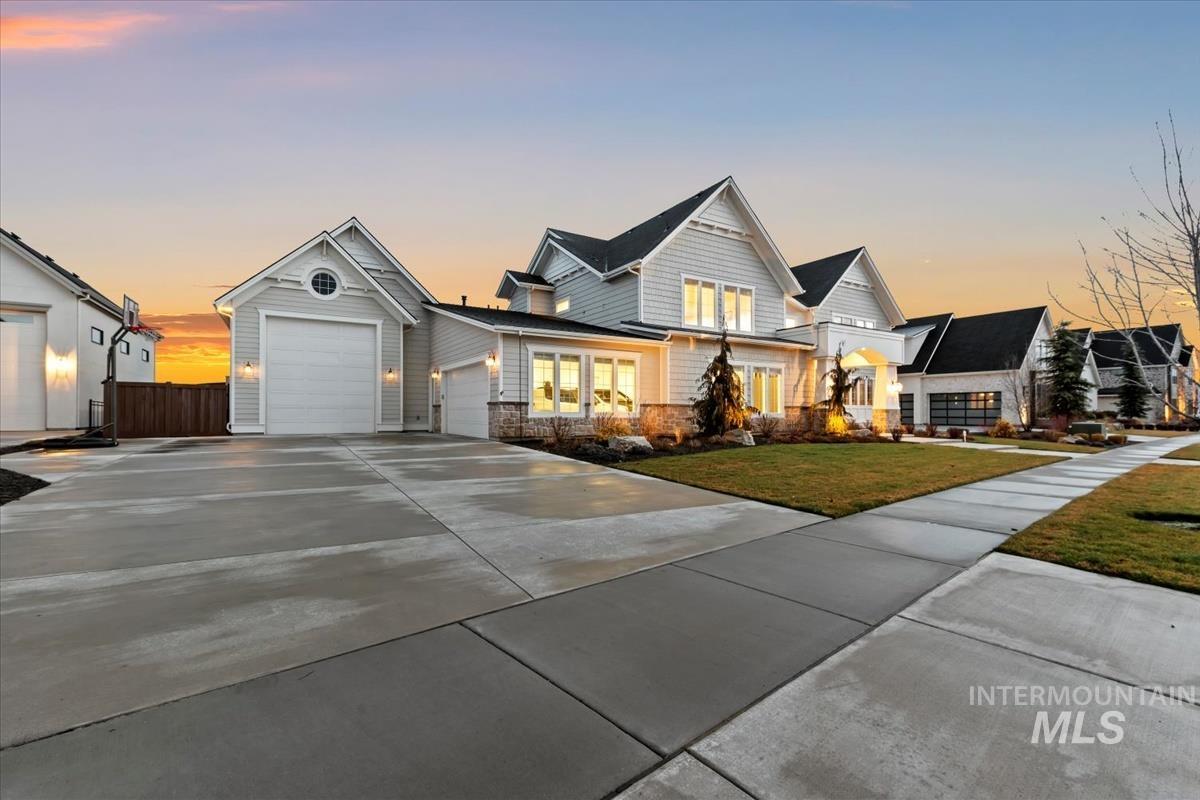 Traditional home featuring concrete driveway, stone siding, a garage, and a front lawn