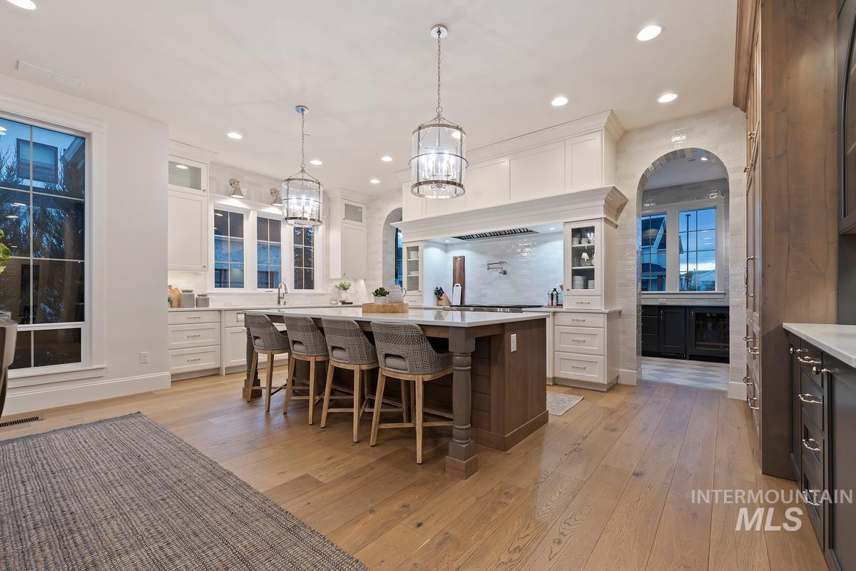 Kitchen with a kitchen breakfast bar, light wood finished floors, glass fronted cabinets, a kitchen island, and dual tone cabinets