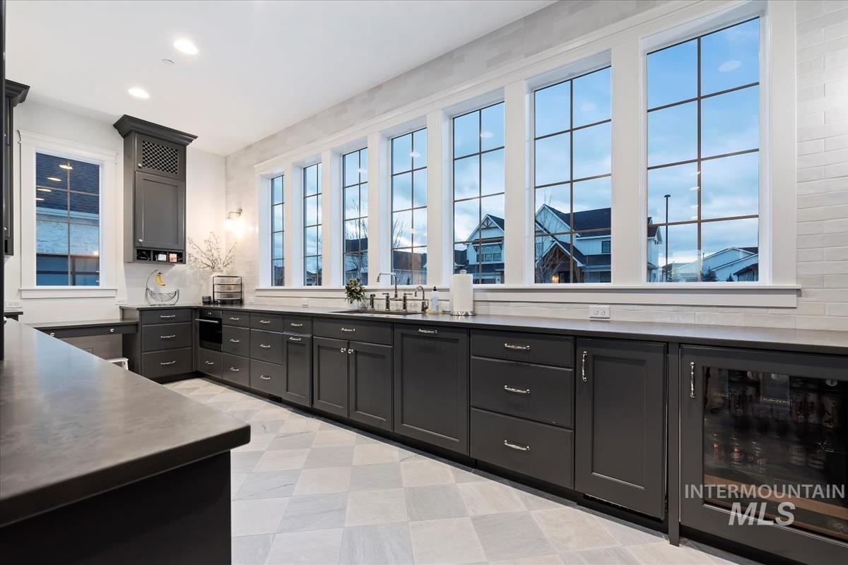 Kitchen featuring wine cooler, dark cabinetry, recessed lighting, and light flooring