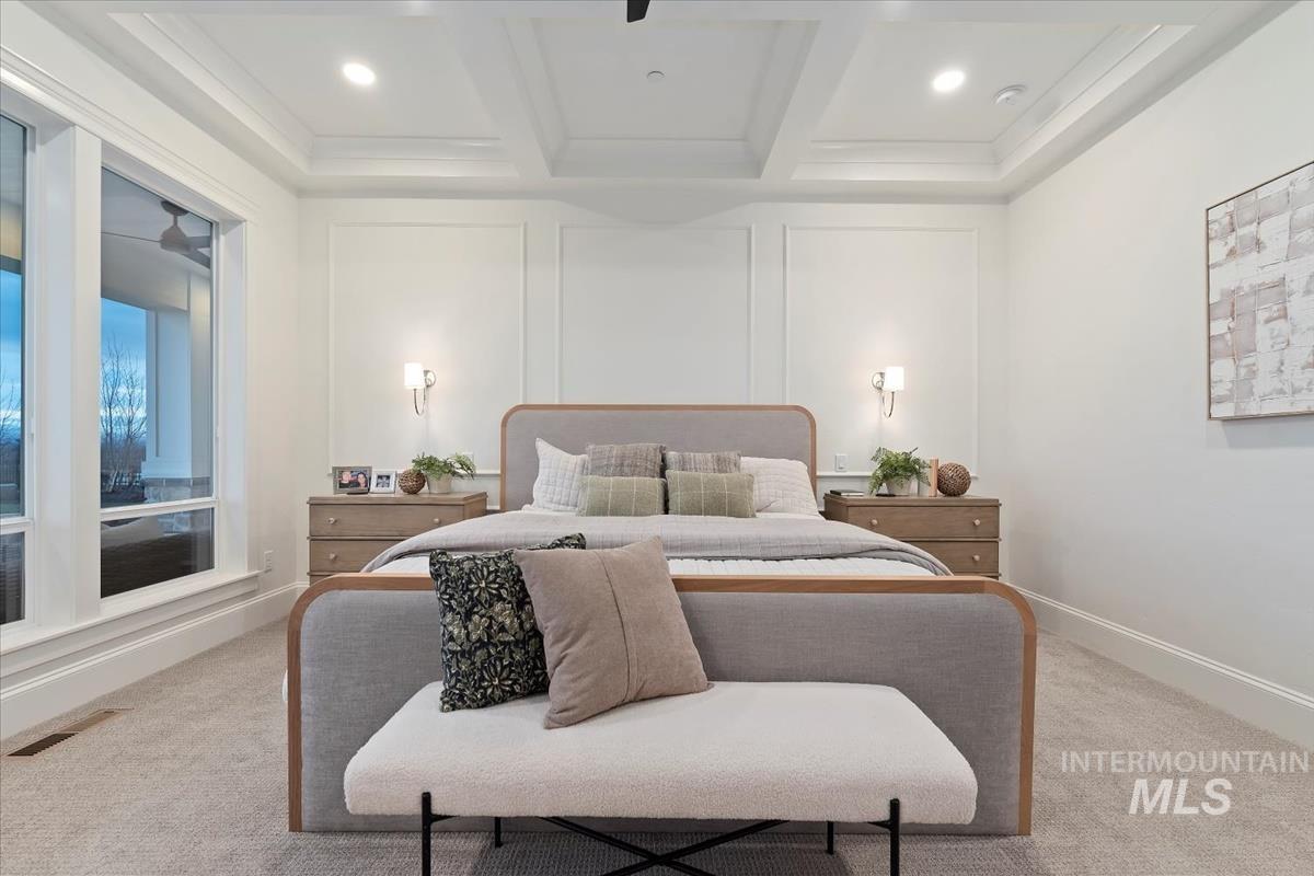 Bedroom featuring a decorative wall, light carpet, and coffered ceiling
