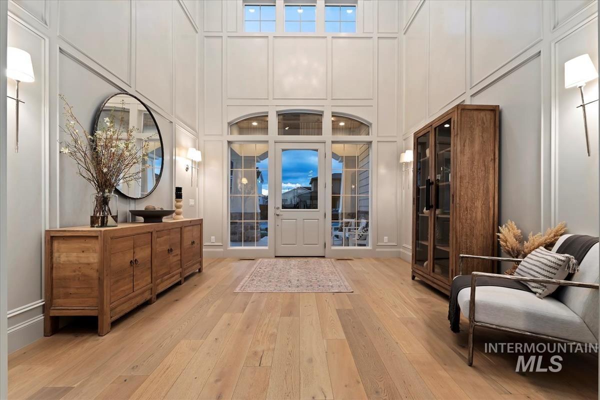 Foyer featuring light wood-style floors, a decorative wall, and a high ceiling
