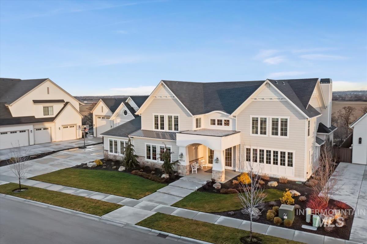 View of front of property with a porch, driveway, a front yard, a garage, and stone siding