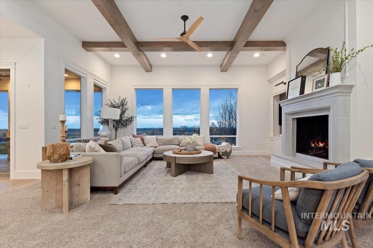 Living room featuring a ceiling fan, a lit fireplace, coffered ceiling, light colored carpet, and recessed lighting