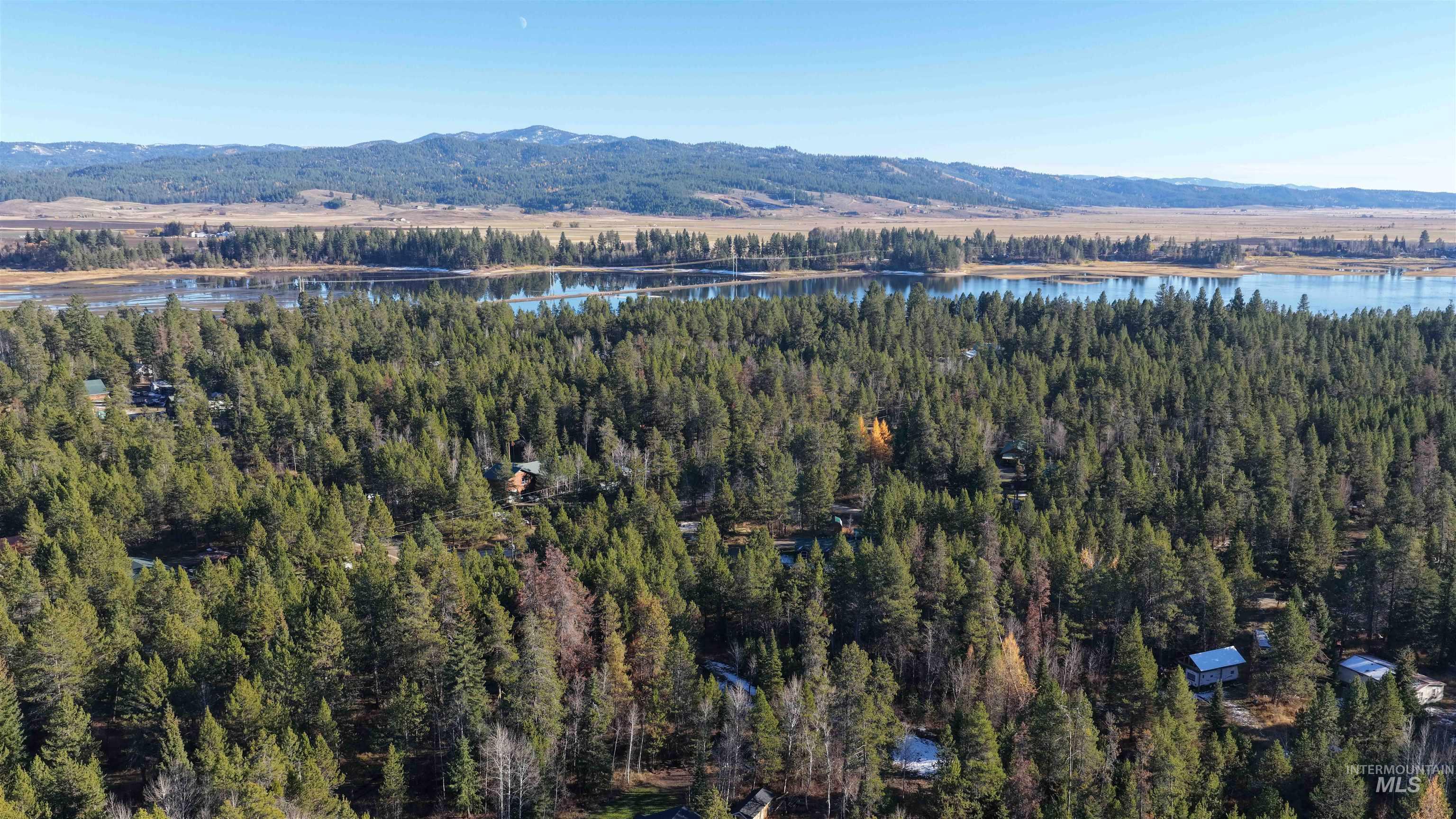 Aerial view of property and surrounding area featuring a water and mountain view and a heavily wooded area