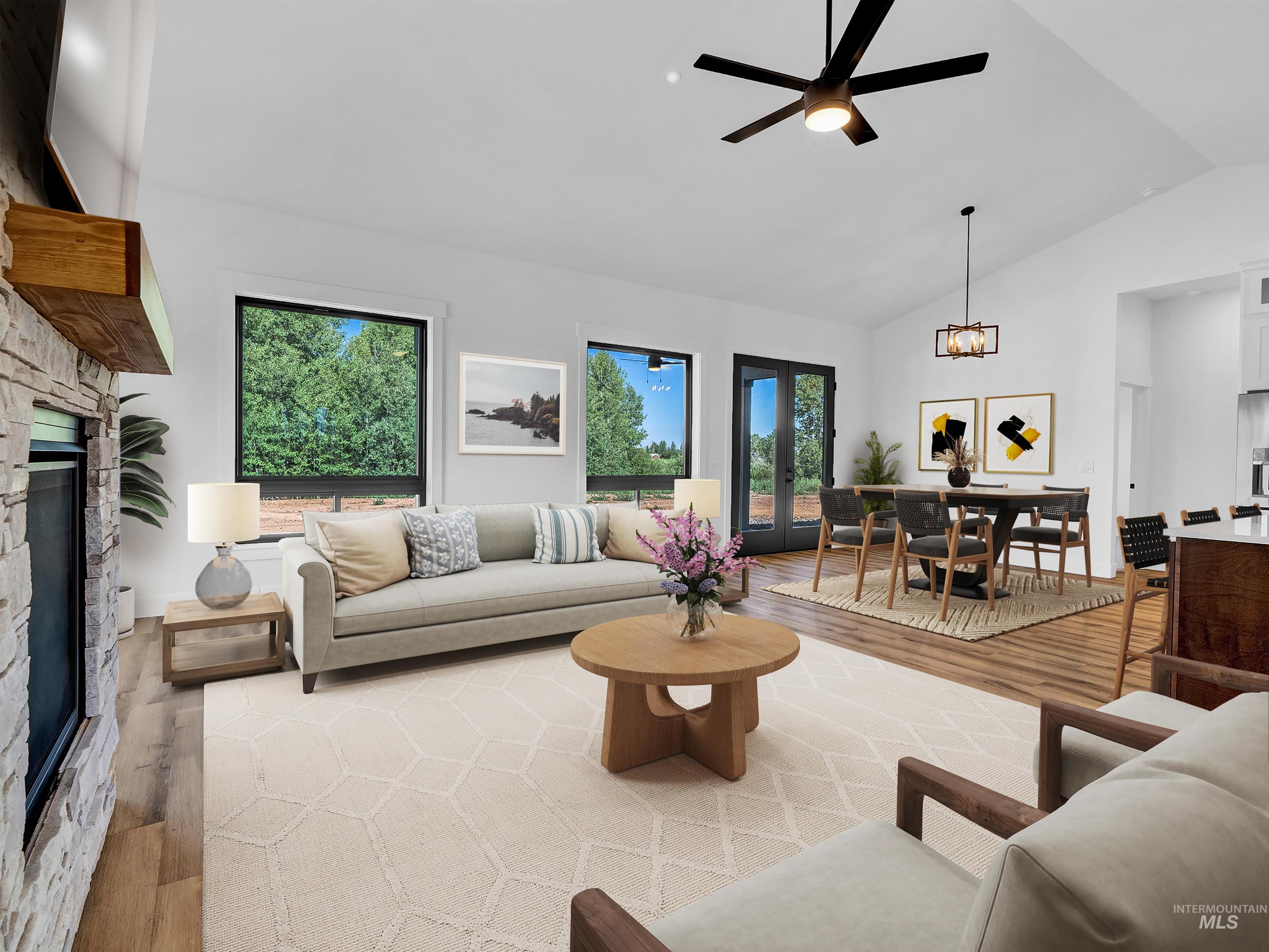 Living room with light wood-style floors, a fireplace, ceiling fan, high vaulted ceiling, and a chandelier