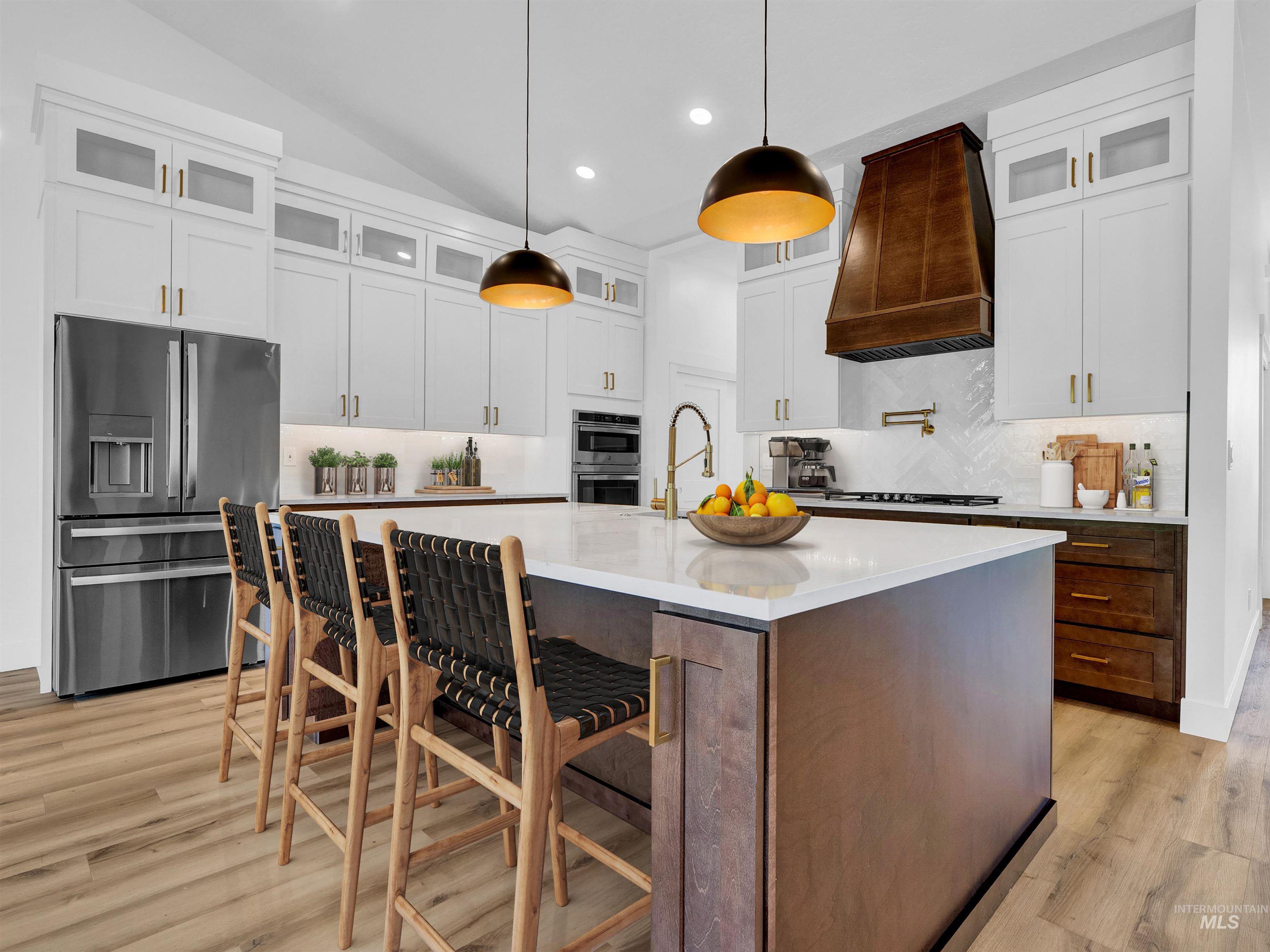Kitchen with stainless steel appliances, light wood-type flooring, backsplash, recessed lighting, and an island with sink