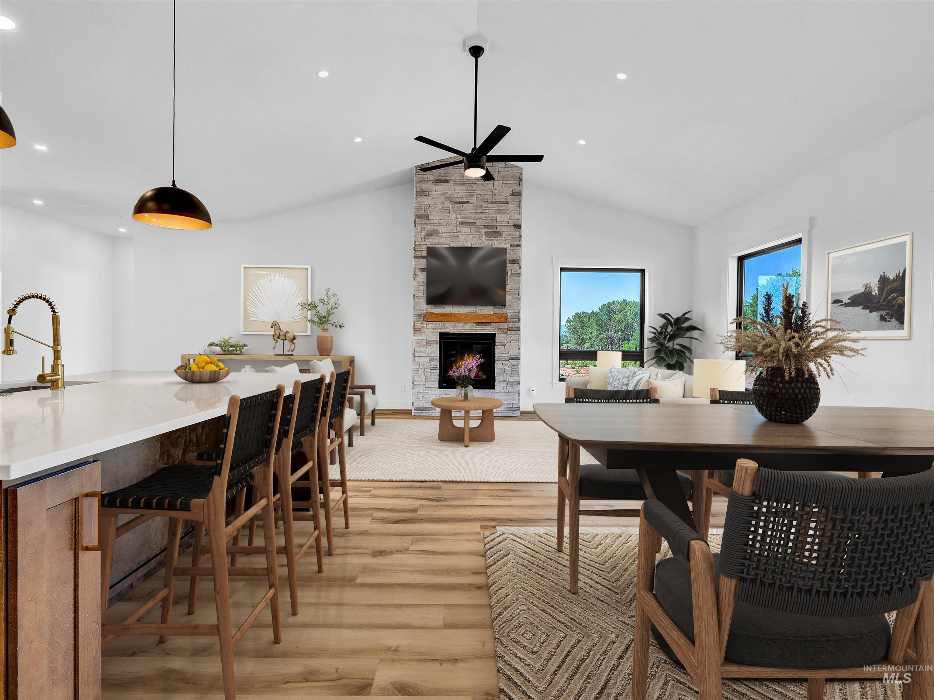 Dining room featuring ceiling fan, light wood finished floors, a stone fireplace, recessed lighting, and lofted ceiling