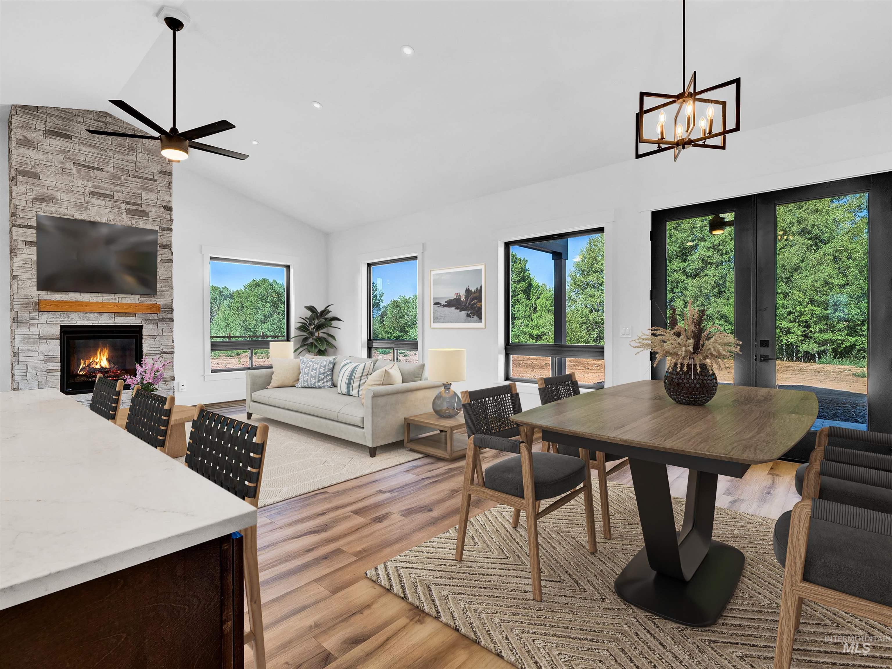 Dining room featuring light wood-style flooring, a stone fireplace, a ceiling fan, a chandelier, and french doors