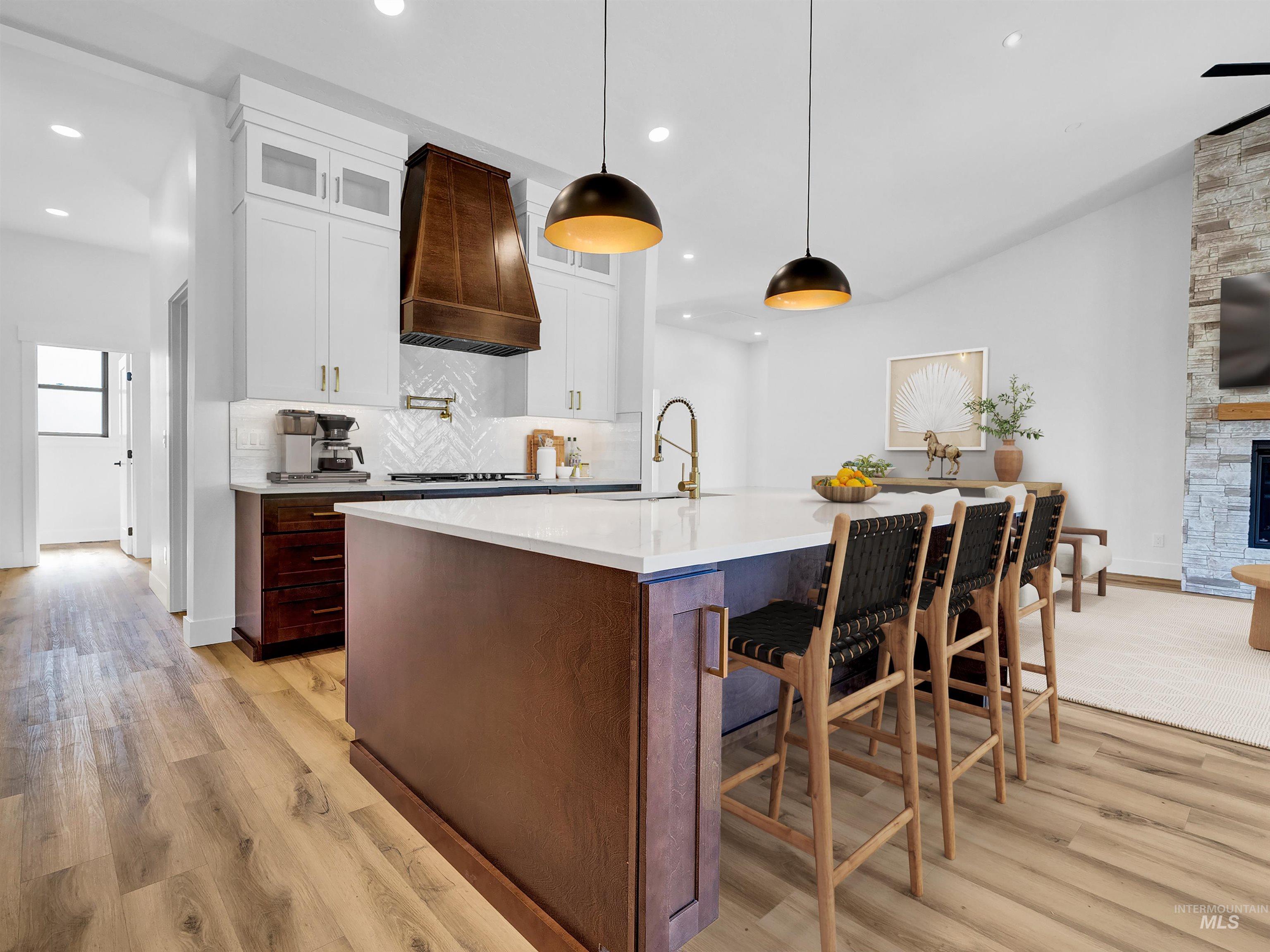 Kitchen featuring light wood-type flooring, tasteful backsplash, light countertops, glass insert cabinets, and recessed lighting