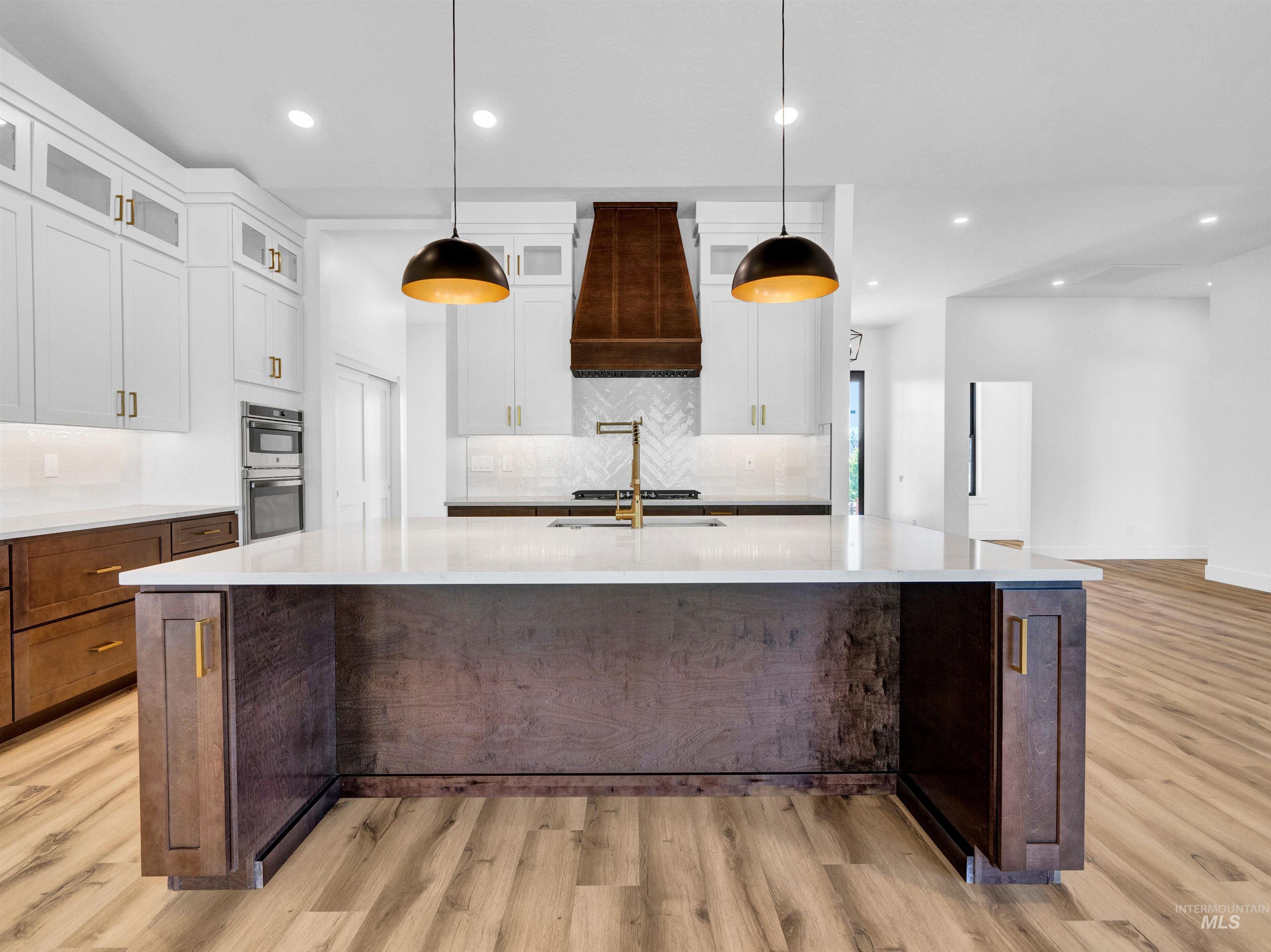 Kitchen with light wood-type flooring, tasteful backsplash, light countertops, and recessed lighting