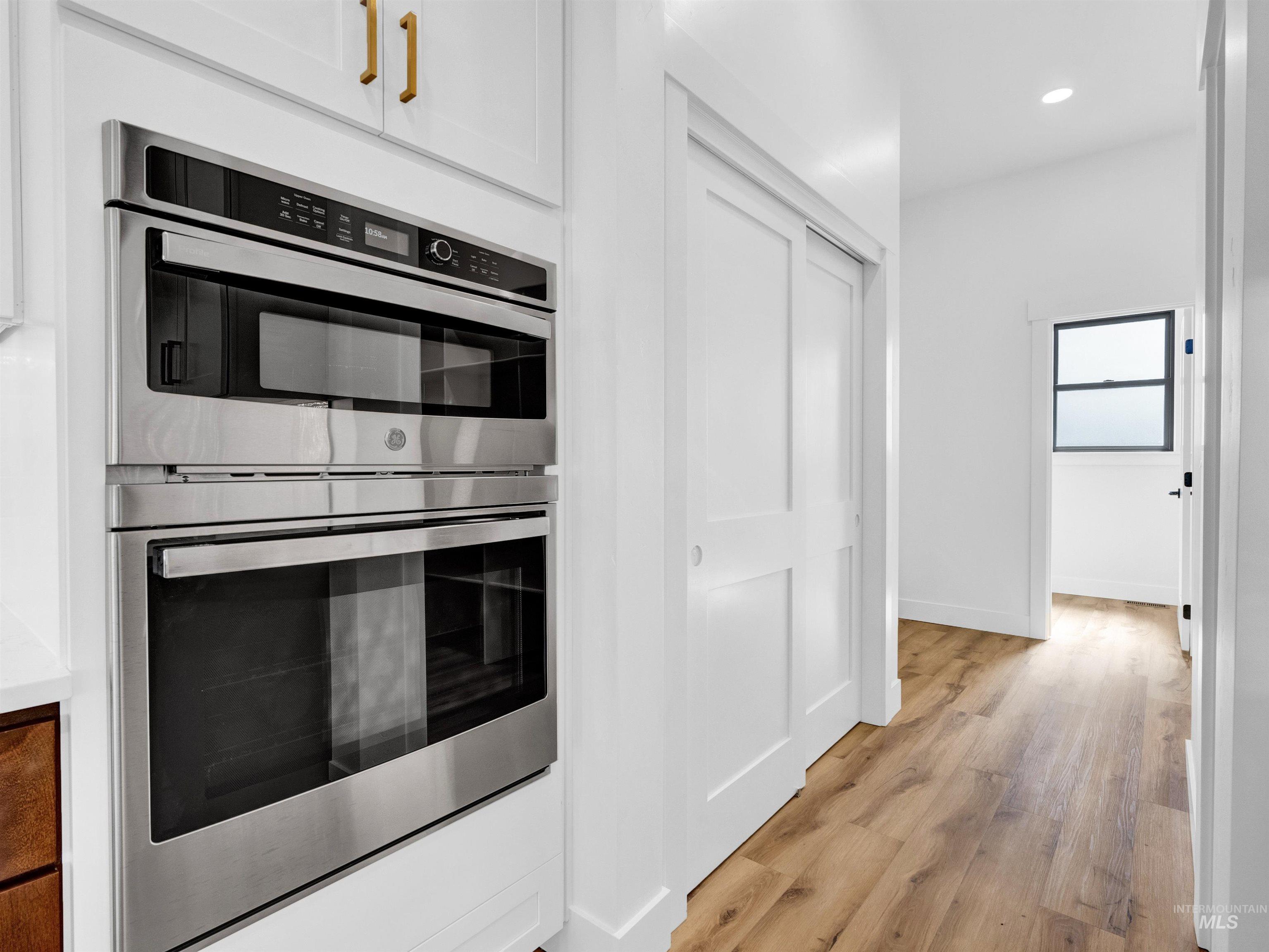 Kitchen with double oven, light wood-style floors, recessed lighting, and white cabinetry