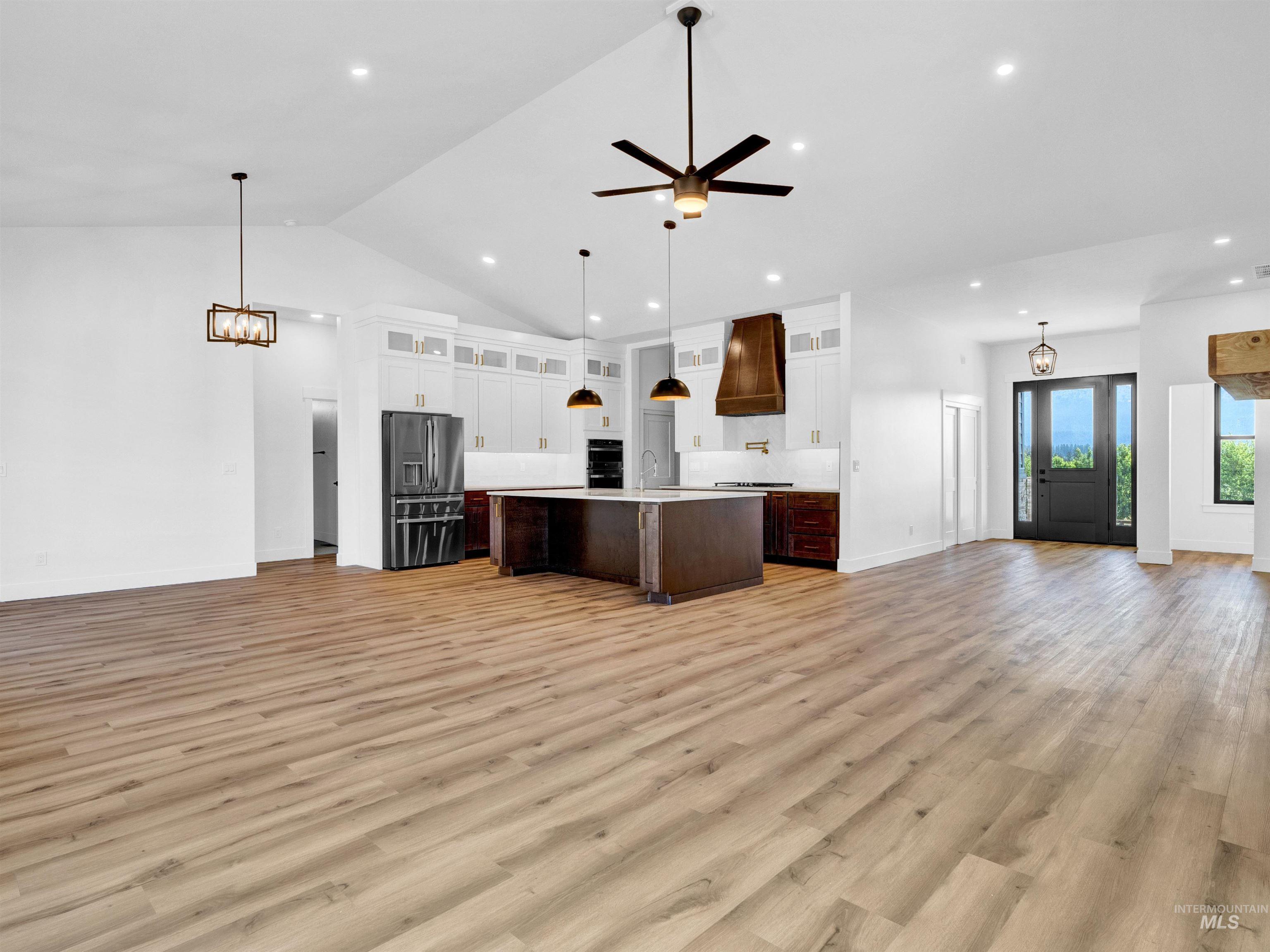 Kitchen with open floor plan, light countertops, recessed lighting, stainless steel fridge with ice dispenser, and light wood-type flooring