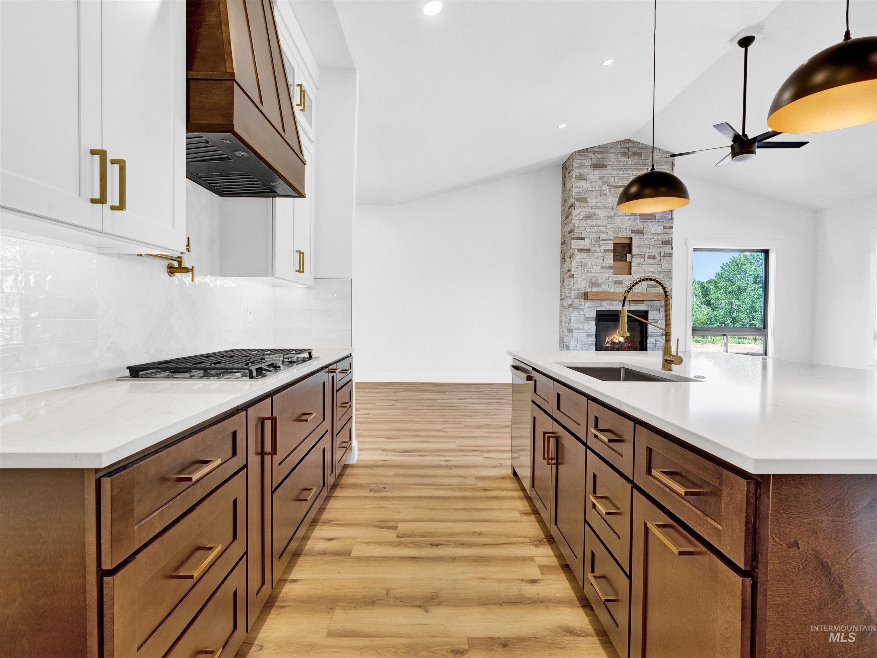 Kitchen featuring a ceiling fan, light wood-style floors, a fireplace, tasteful backsplash, and white cabinetry