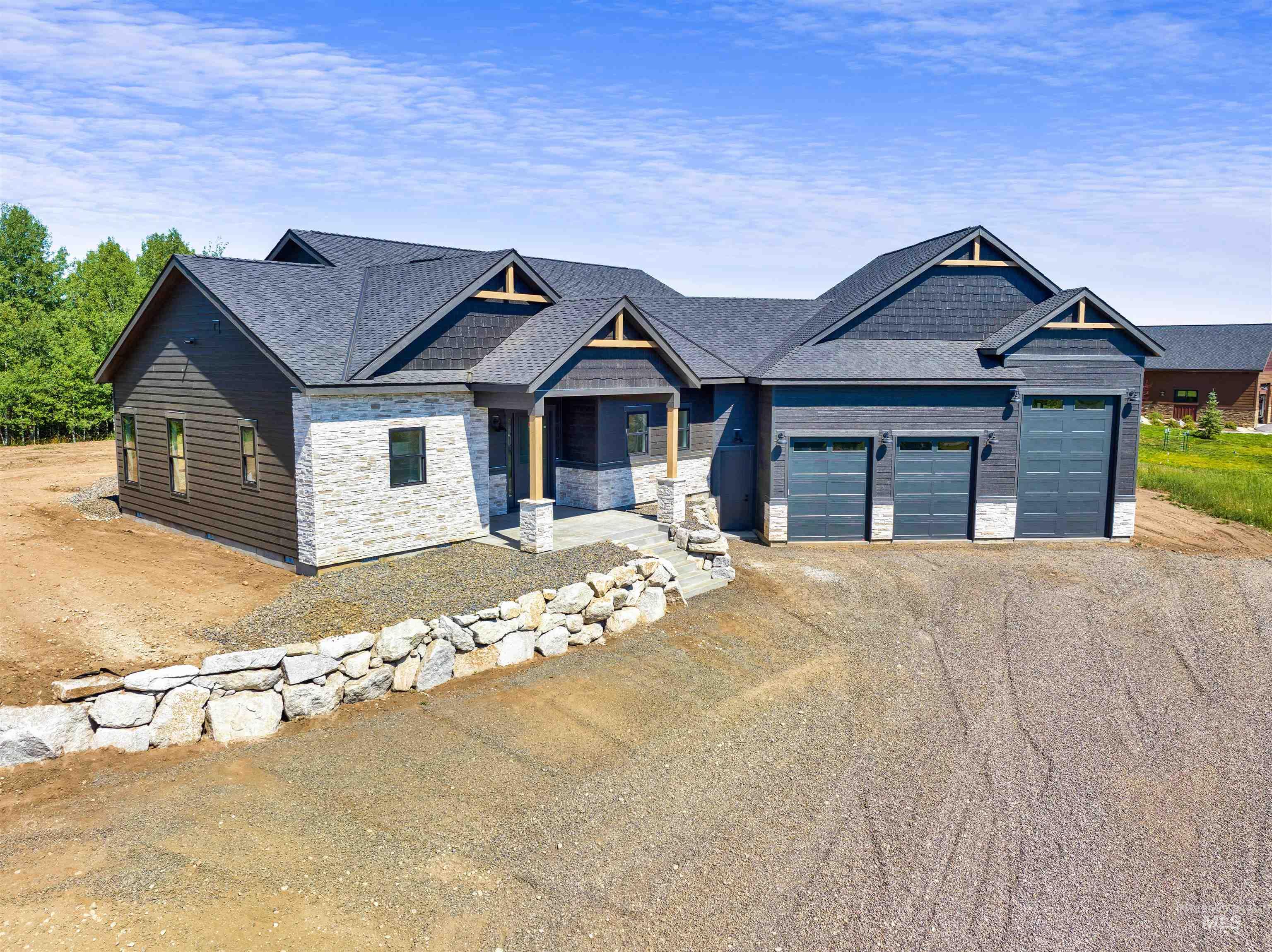 Craftsman-style home with stone siding, driveway, an attached garage, and covered porch