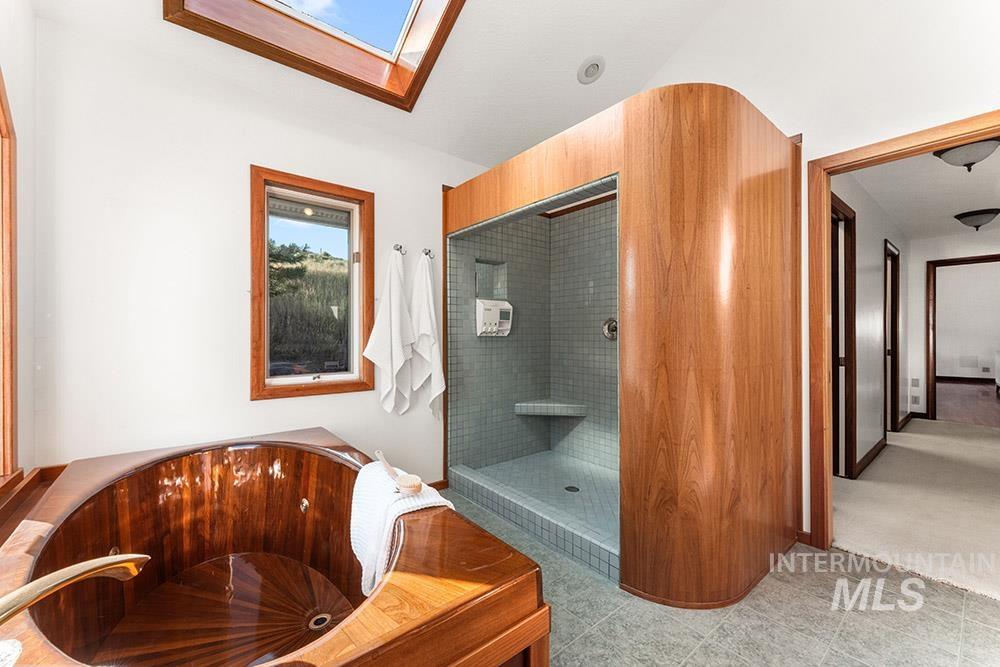 Bathroom with a skylight, a whirlpool tub, and a walk in shower