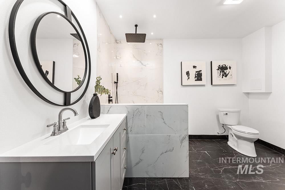 Full bath featuring marble tiled flooring, vanity, a marble finish shower, and recessed lighting