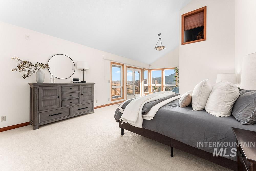Bedroom with light carpet and high vaulted ceiling