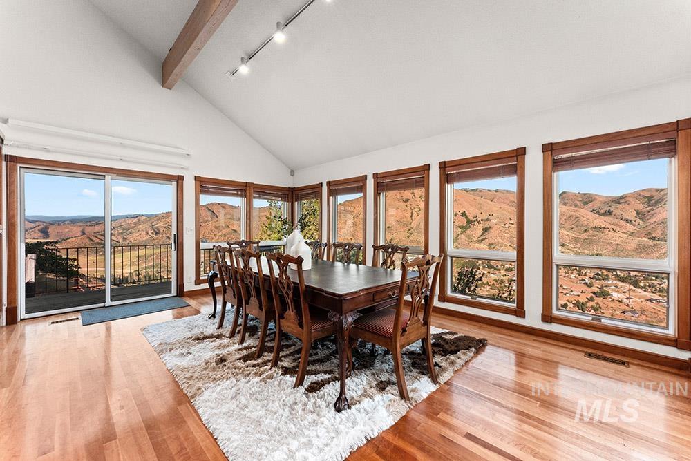 Dining room featuring beamed ceiling, wood finished floors, track lighting, a mountain view, and high vaulted ceiling