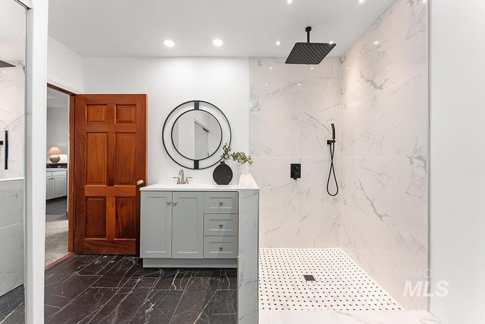 Full bathroom featuring marble tiled flooring, vanity, a marble finish shower, and recessed lighting