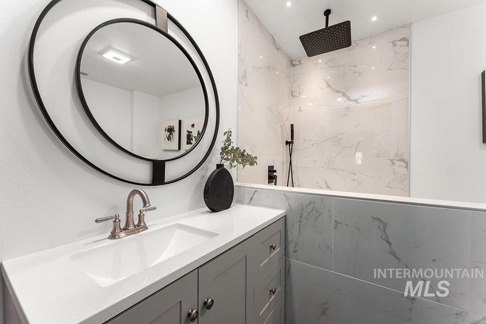 Bathroom featuring vanity and a marble finish shower