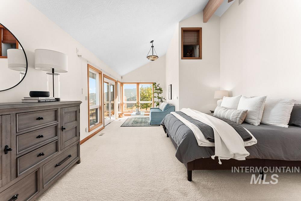 Bedroom featuring light colored carpet, beamed ceiling, access to exterior, and high vaulted ceiling