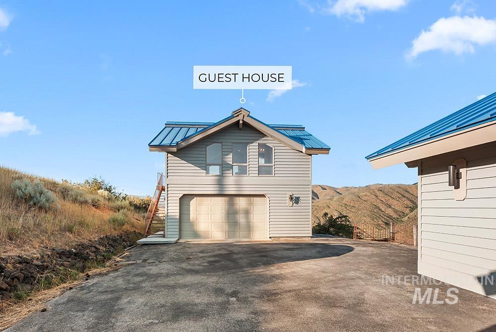 View of side of property featuring a standing seam roof, a metal roof, driveway, an attached garage, and stairway