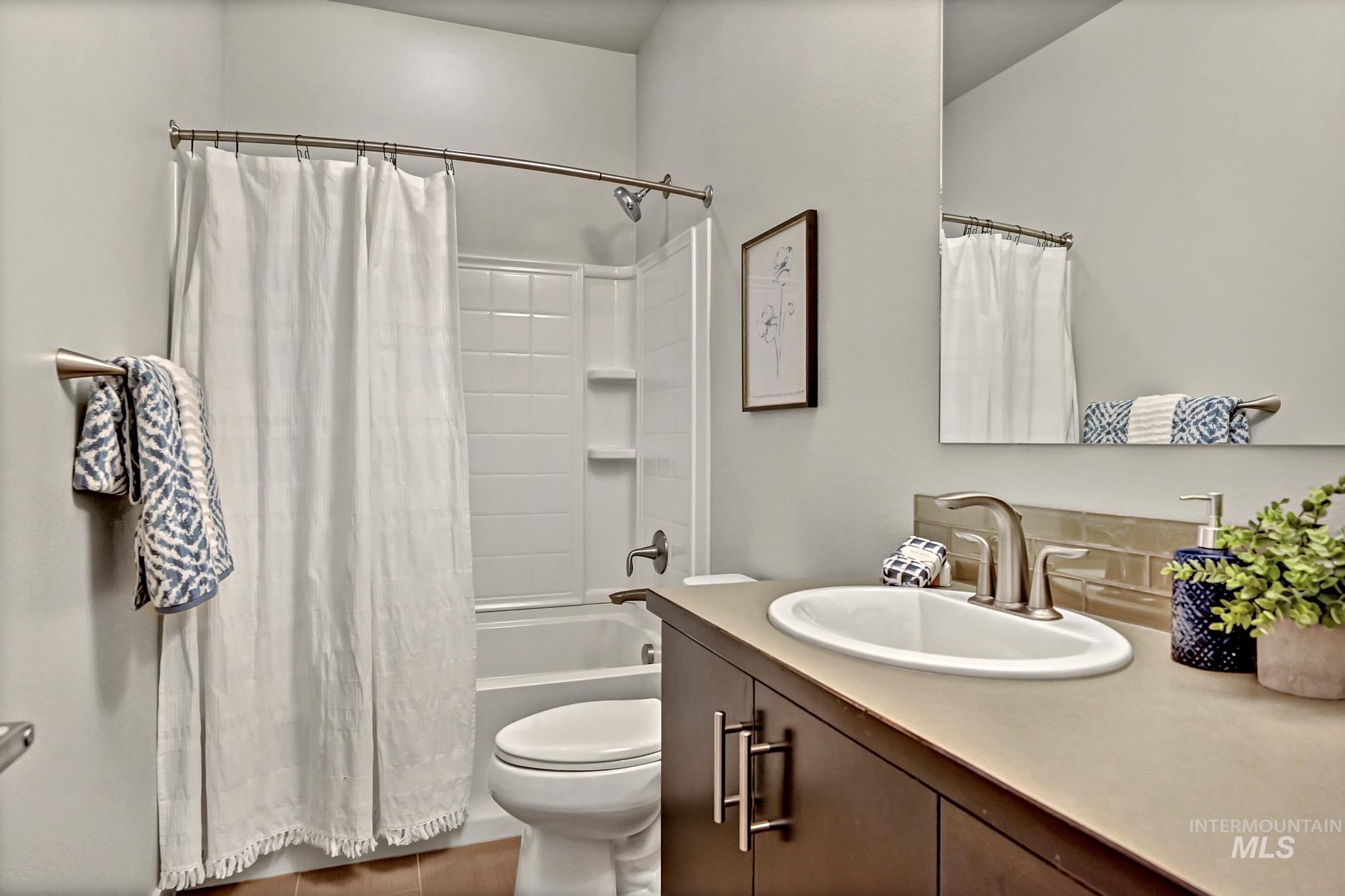 Bathroom with shower / bath combination with curtain, vanity, and tasteful backsplash